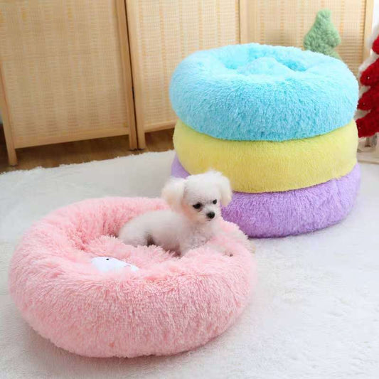Pastel-colored pet bed with a small white dog inside on a light wooden floor.