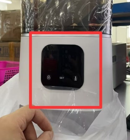 White electronic device with a screen, held by a hand, wrapped in plastic.