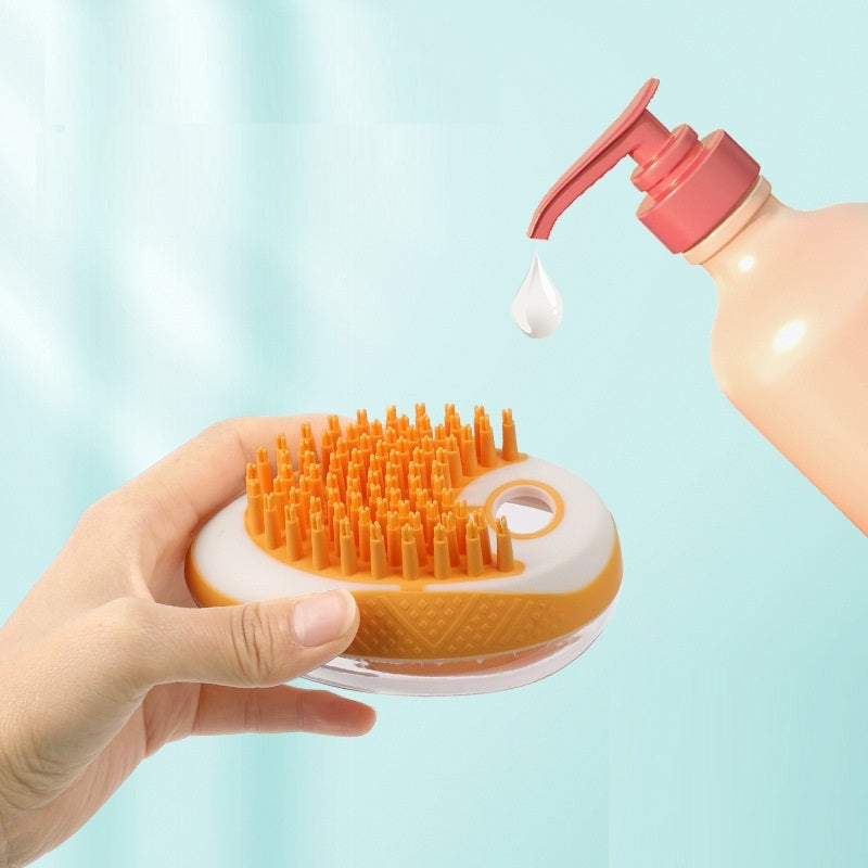 Hand holding a hair scrubber with an orange bristle brush and a pink bottle dispensing liquid.