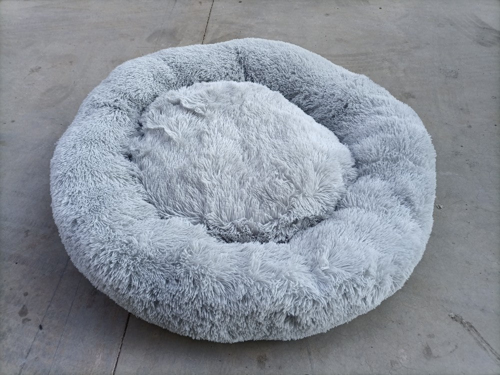 Fluffy gray pet bed on a concrete surface