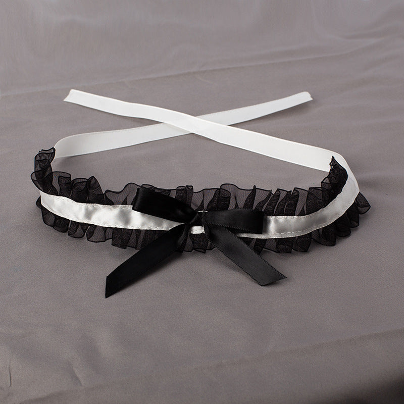 Black garter with white satin ribbon on a gray background