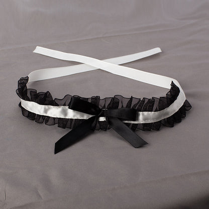 Black garter with white satin ribbon on a gray background
