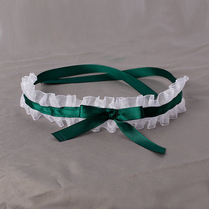White lace headband with a green ribbon on a gray background